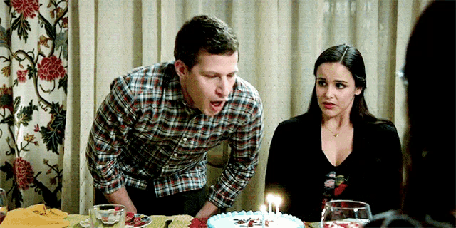 a man and a woman are sitting at a table with a birthday cake