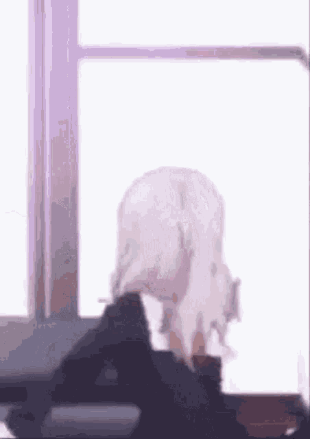 a woman with white hair is standing in front of a window looking out .