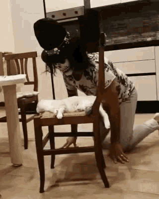 a woman in a skeleton costume is kneeling down next to a chair with a cat laying on it .