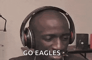 a man wearing headphones is sitting in front of a microphone and says `` go eagles '' .