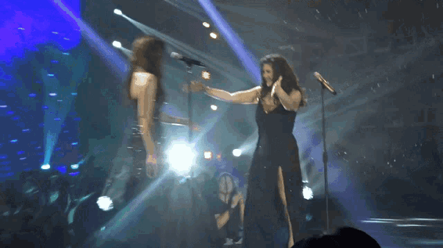 two women singing on a stage with a purple background that says zlrj