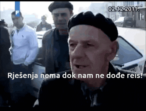 a man in a black hat is talking to another man in a white shirt with the date 02.12.2011