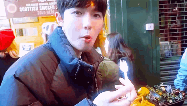 a boy is eating food in front of a sign that says " scottish smoked "