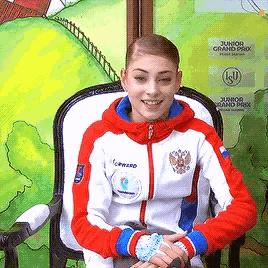 a girl in a red white and blue jacket sits in a chair