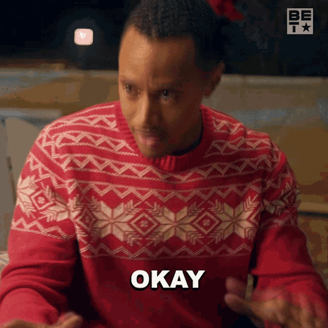 a man in a red sweater says okay with his hands outstretched