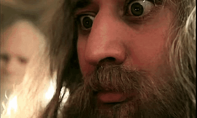 a close up of a man 's face with a beard making a funny face