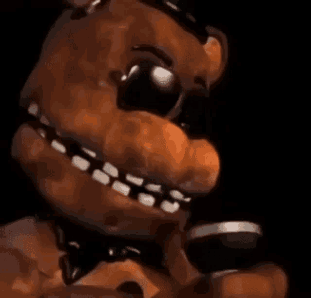 freddy fazbear from five nights at freddy 's is holding a microphone in his hand in a dark room .