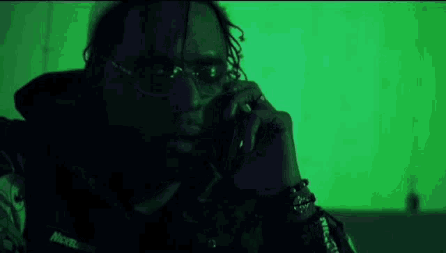 a man wearing sunglasses is talking on a cell phone in a dark room .
