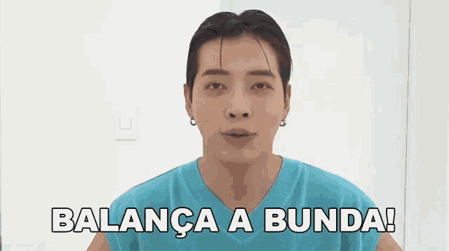 a man in a blue shirt is standing in front of a white wall and says balance a bunda !