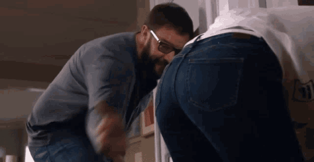 a man wearing glasses looks at a woman 's butt