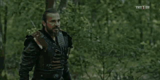 a man holding a sword in the woods with trt 1 hd written above him