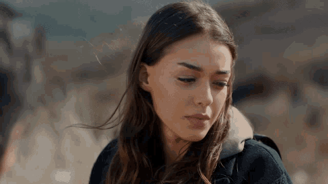a woman in a black jacket looks down at something