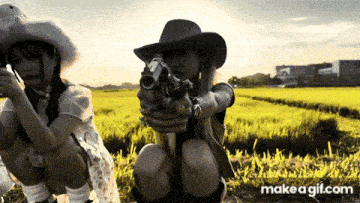 a woman in a cowboy hat is holding a gun in a field