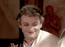 a man with curly hair and a white shirt is smiling
