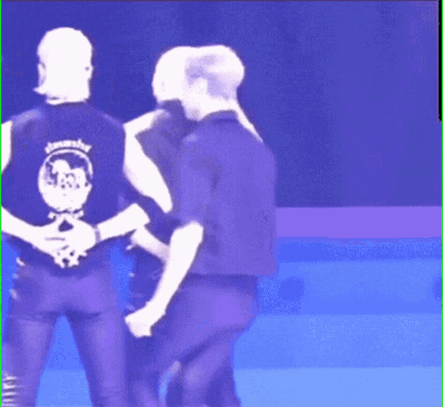a couple of men are standing next to each other on a stage in a dark room .