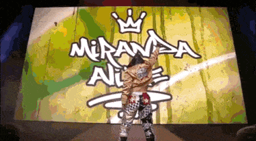 a person is standing in front of a large screen that says miranda nice