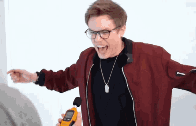 a man wearing glasses and a red jacket is holding a yellow device
