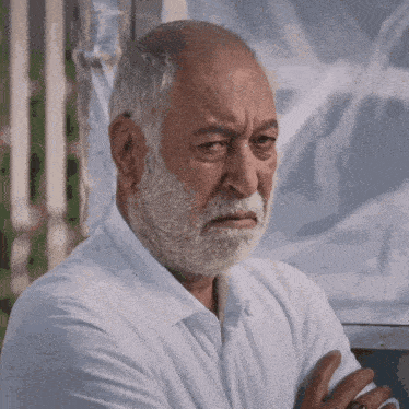 a man with a beard and a white shirt is looking at the camera
