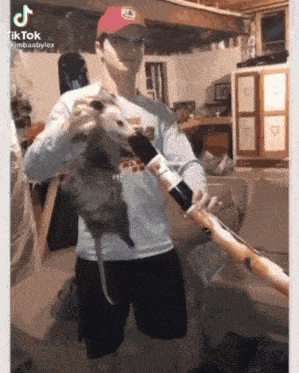 a man is holding a large opossum in his hands