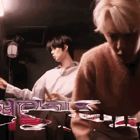 two men are sitting at a table in a dark room playing a game .