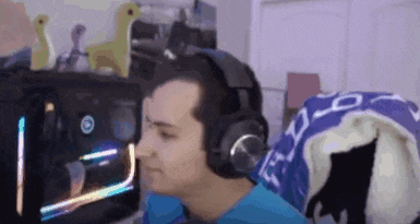 a man wearing headphones is sitting in front of a computer and looking at the screen .