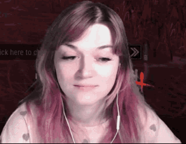a woman with pink hair is wearing ear buds and looking at the camera