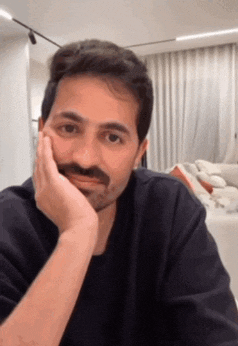 a man with a beard rests his hand on his chin