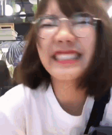a woman wearing glasses and a white shirt is making a face