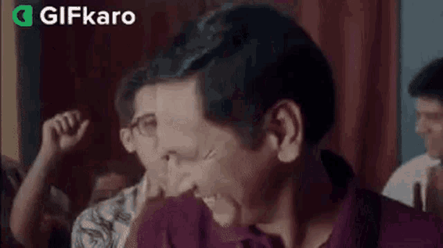 a group of people are laughing and applauding while a man is eating something .