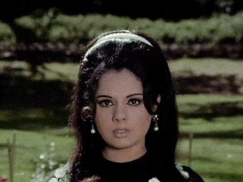 a woman wearing a headband and earrings is standing in a field