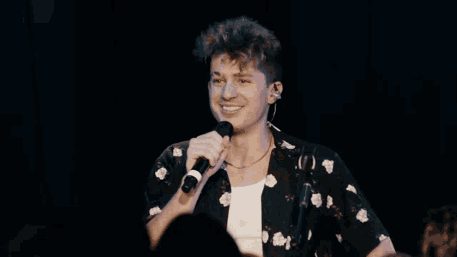 a man singing into a microphone with a crowd behind him