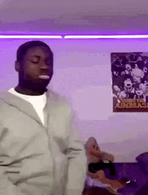 a man is dancing in a room with purple lights and a poster on the wall that says ' avengers ' .