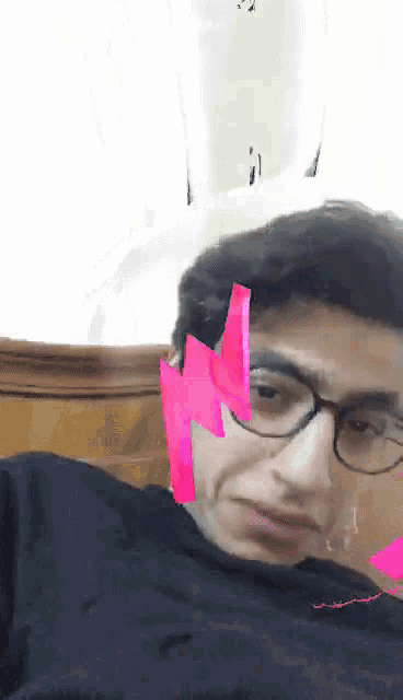 a man wearing glasses has a pink lightning bolt on his ear