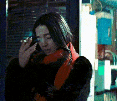 a woman is smoking a cigarette while talking on a cell phone .