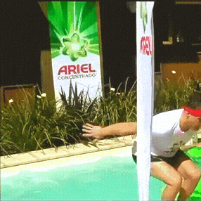 a man is jumping into a pool in front of a sign that says ariel