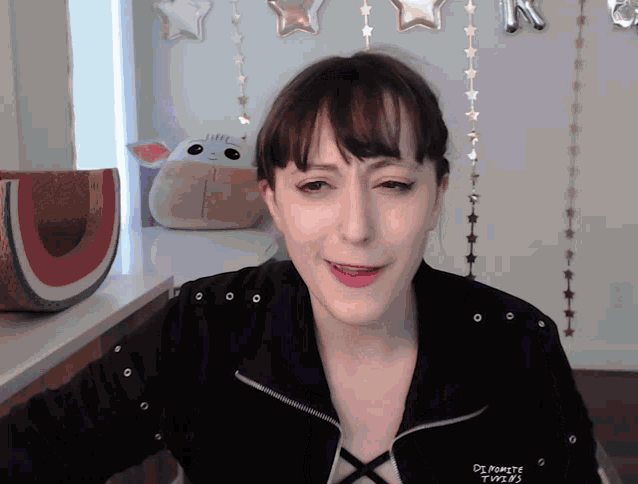 a woman wearing a black jacket that says " dreaming twins "