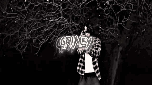 a man in a plaid shirt is standing in front of a tree with the word grimey above him
