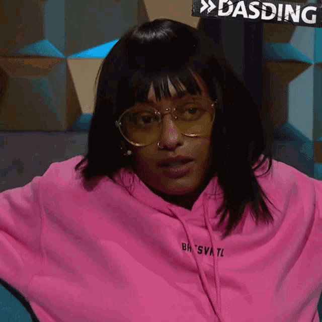 a woman wearing sunglasses and a pink hoodie with the word dasding on the front