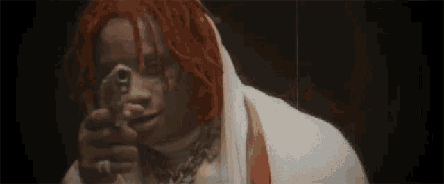 a man with red hair is holding a gun to his face