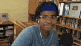 a man wearing headphones and a headband is sitting in front of a microphone .