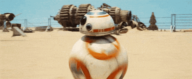 a bb-8 robot is standing on a sandy field