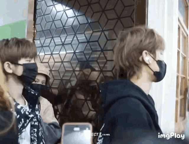 a group of people wearing face masks are standing in front of a door and a phone that says imgplay