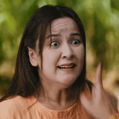 a woman with a surprised look on her face is making a funny face and pointing her finger .