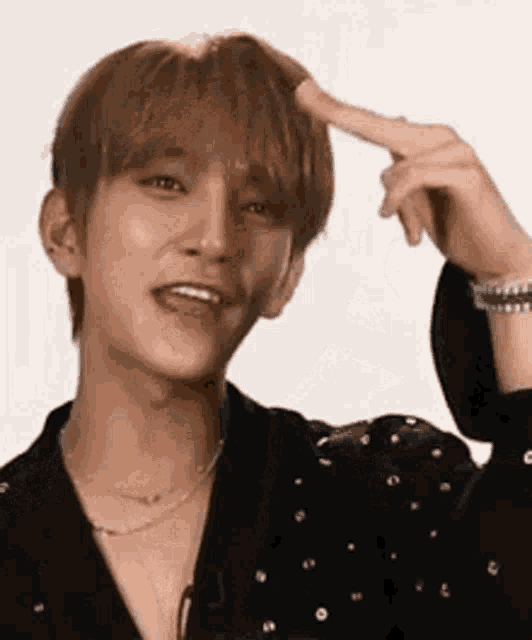 a young man is making a funny face and pointing at his head .
