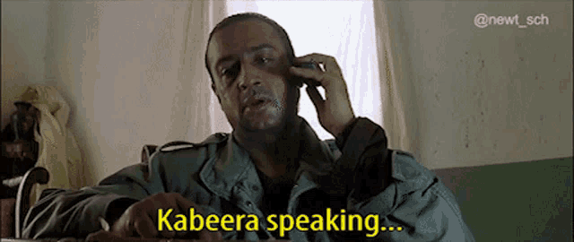 a man is talking on a cell phone and says " kabeera speaking " in yellow letters