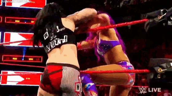two women are wrestling in a wrestling ring and one of them is wearing a purple top .