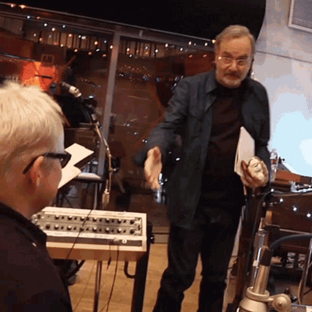 a man with glasses is shaking hands with another man in front of a keyboard