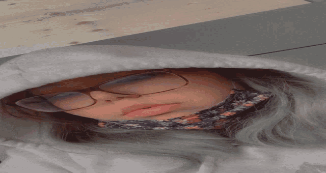 a woman wearing glasses and a floral headband is sleeping