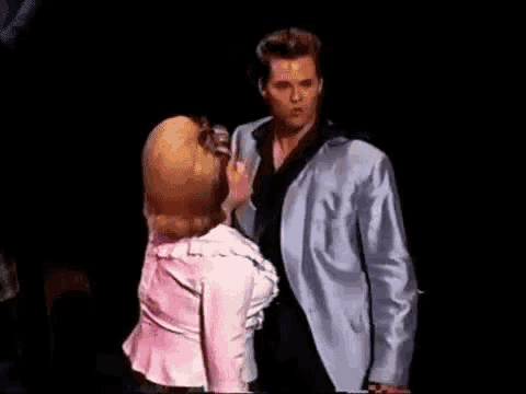 a man and woman are kissing on a stage .