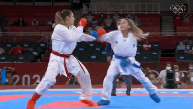 two women are fighting each other in a karate match on a mat .